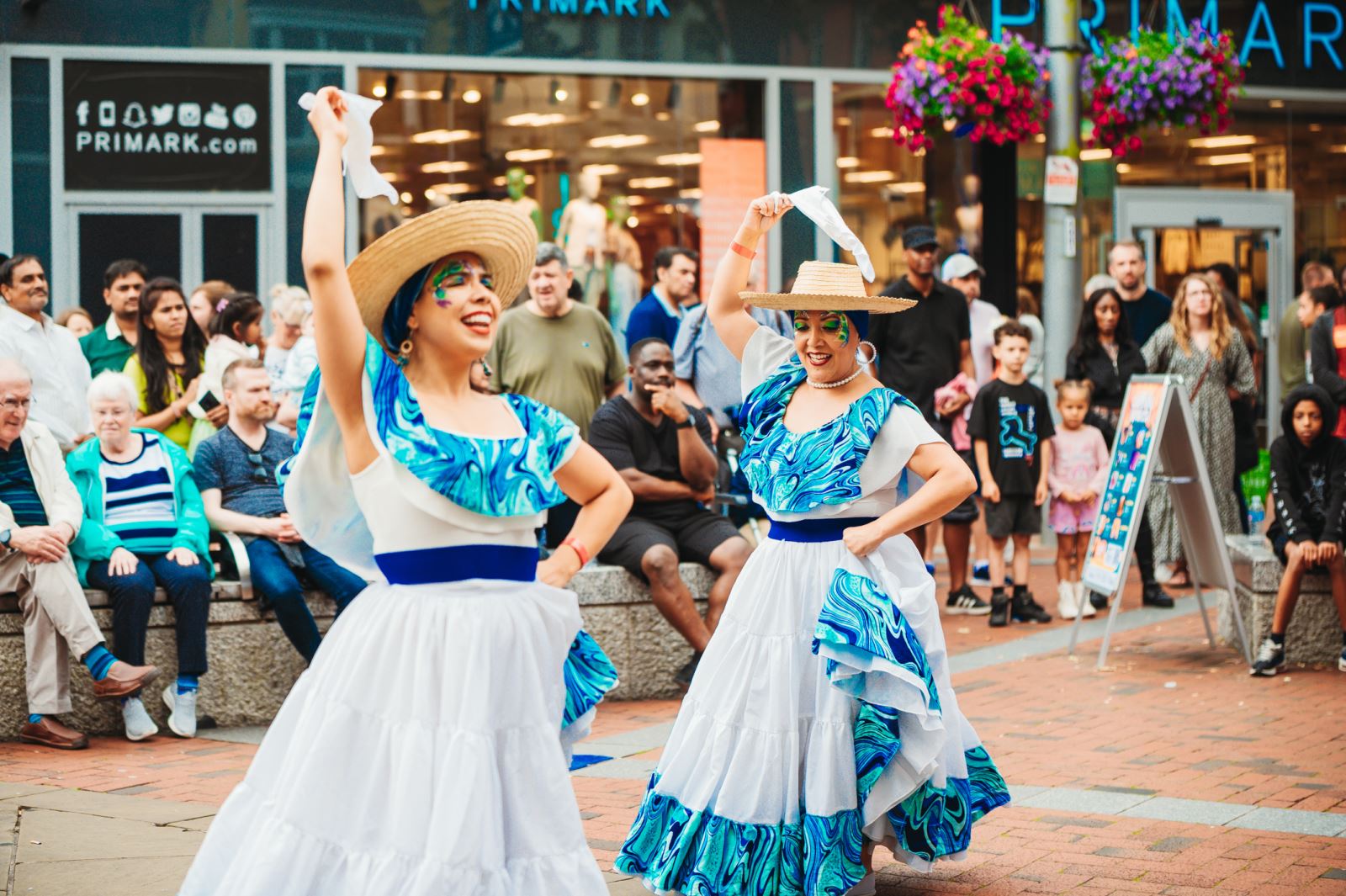 Two ladies in white and blue dresses dancing on the high street